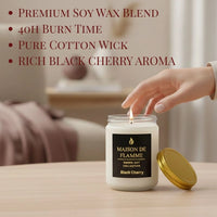 Thumbnail for Hand reaching for the white Black Cherry candle on a wooden table — fruity deep cherry home fragrance.