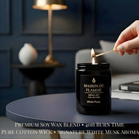 Thumbnail for Hand lighting the black Maison De Flamme White Musk candle on a dark navy table — soft clean musk home fragrance.