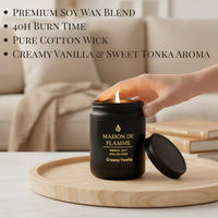 Thumbnail for Hand reaching the black Creamy Vanilla scented candle — cozy warm vanilla home fragrance.