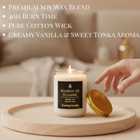 Thumbnail for Hand reaching the white Creamy Vanilla scented candle on a warm-toned tabletop — cozy creamy vanilla home fragrance.