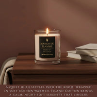 Thumbnail for Island Cotton candle on wooden table with soft fabric, calm warm neutral home fragrance vibe.
